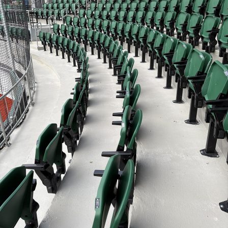 Rangées de sièges de gradin verts suivant la courbe des estrades du stade Richard-Desmeules.