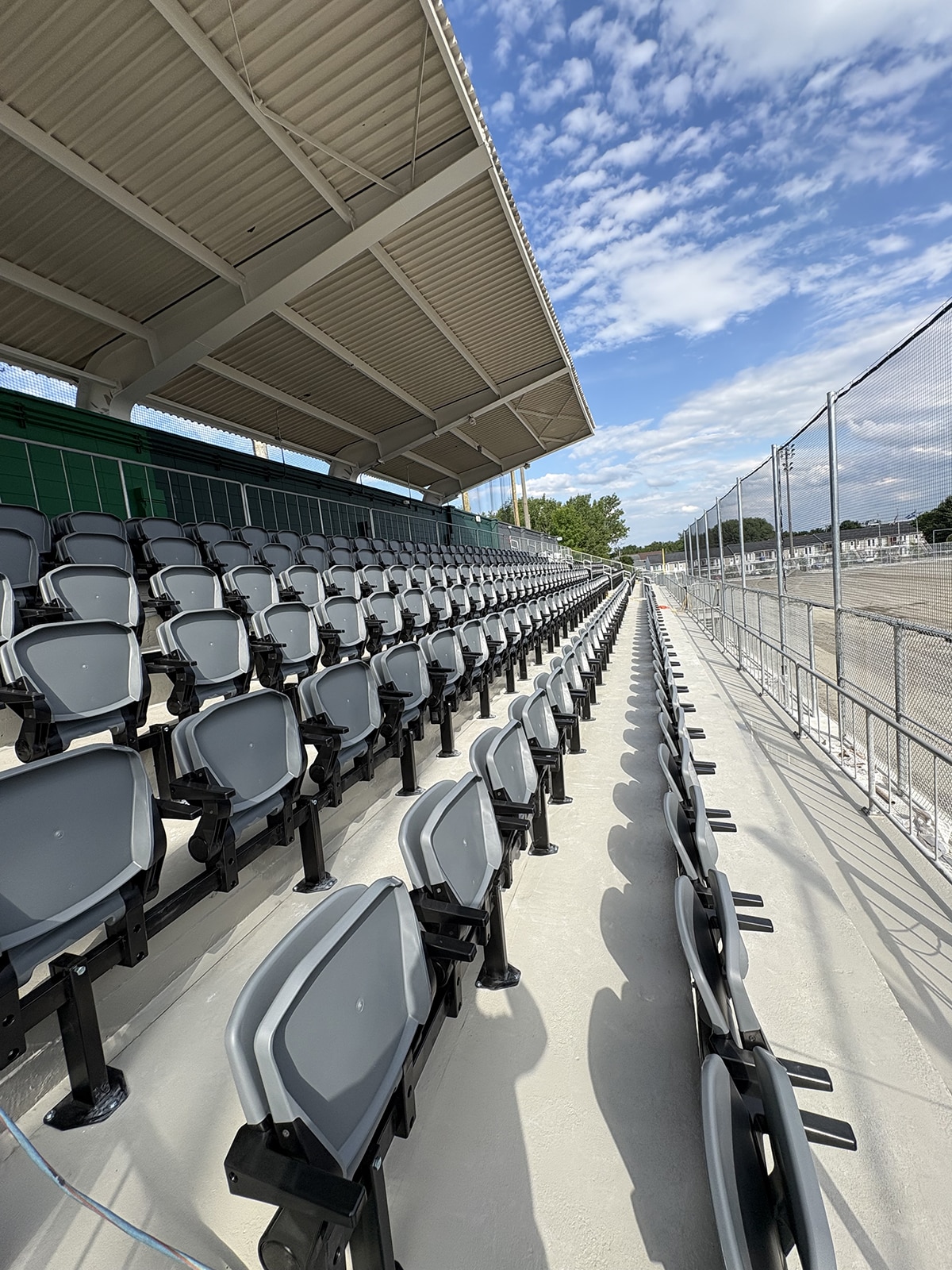Rangées de sièges gris sous un toit du stade Richard-Desmeules.